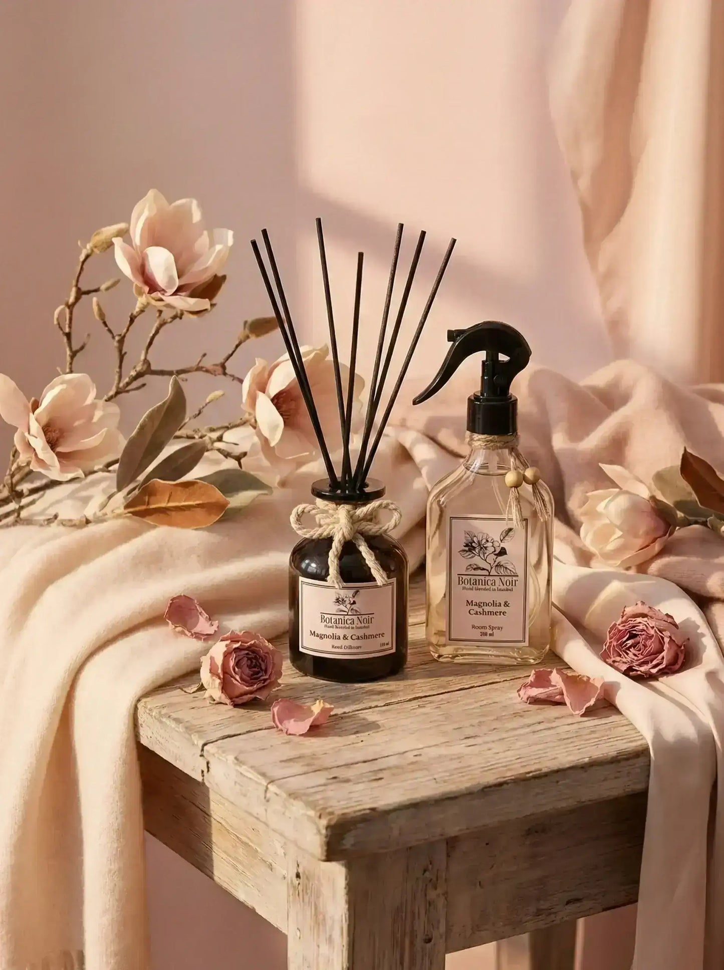 Magnolia ve kaşmir oda spreyi ve reed diffuser, rustik masada çiçeklerle dekorlu.